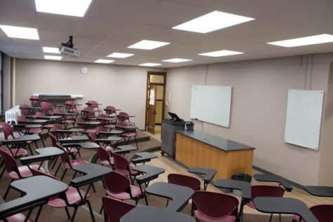 Science Hall room 310 with a view from the student's perspective in the back corner. White boards and the professor's podium can be seen.