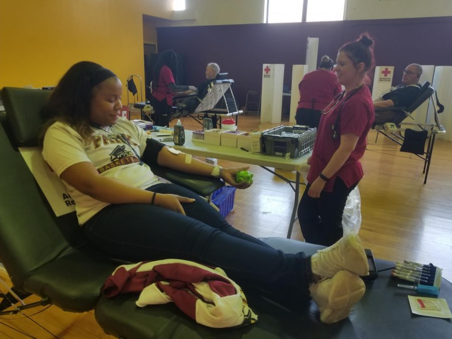 Biology senior Brooklyn Campbell laying on a hospital bed giving blood for the american red cross