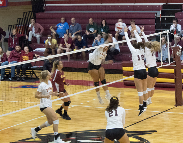 Pirate's player Noura Meawad spikes the ball. Two Buccaneer's players jump up to try to block the ball.
