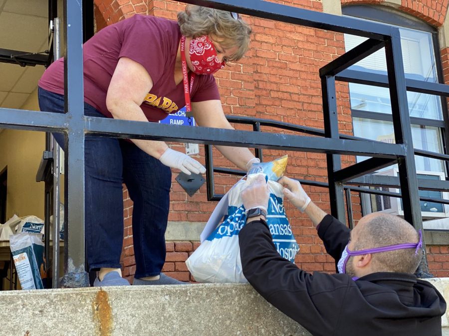 Laurie Gunderson, Park University’s first lady, passes a bag of pantry goods to Dean of Students, Jayme Uden, Ed.D., during a Friday evening pickup for Pirate Pantry.
