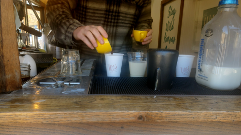 worker pours espresso into coffee